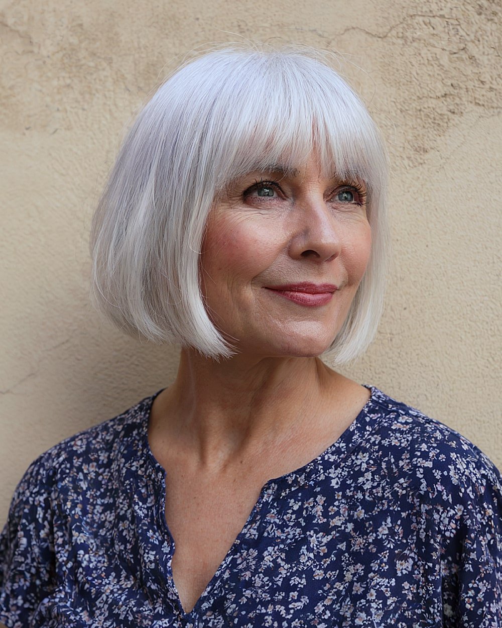 Classic chin-length bob for older women with full fringe and sleek silver-white finish