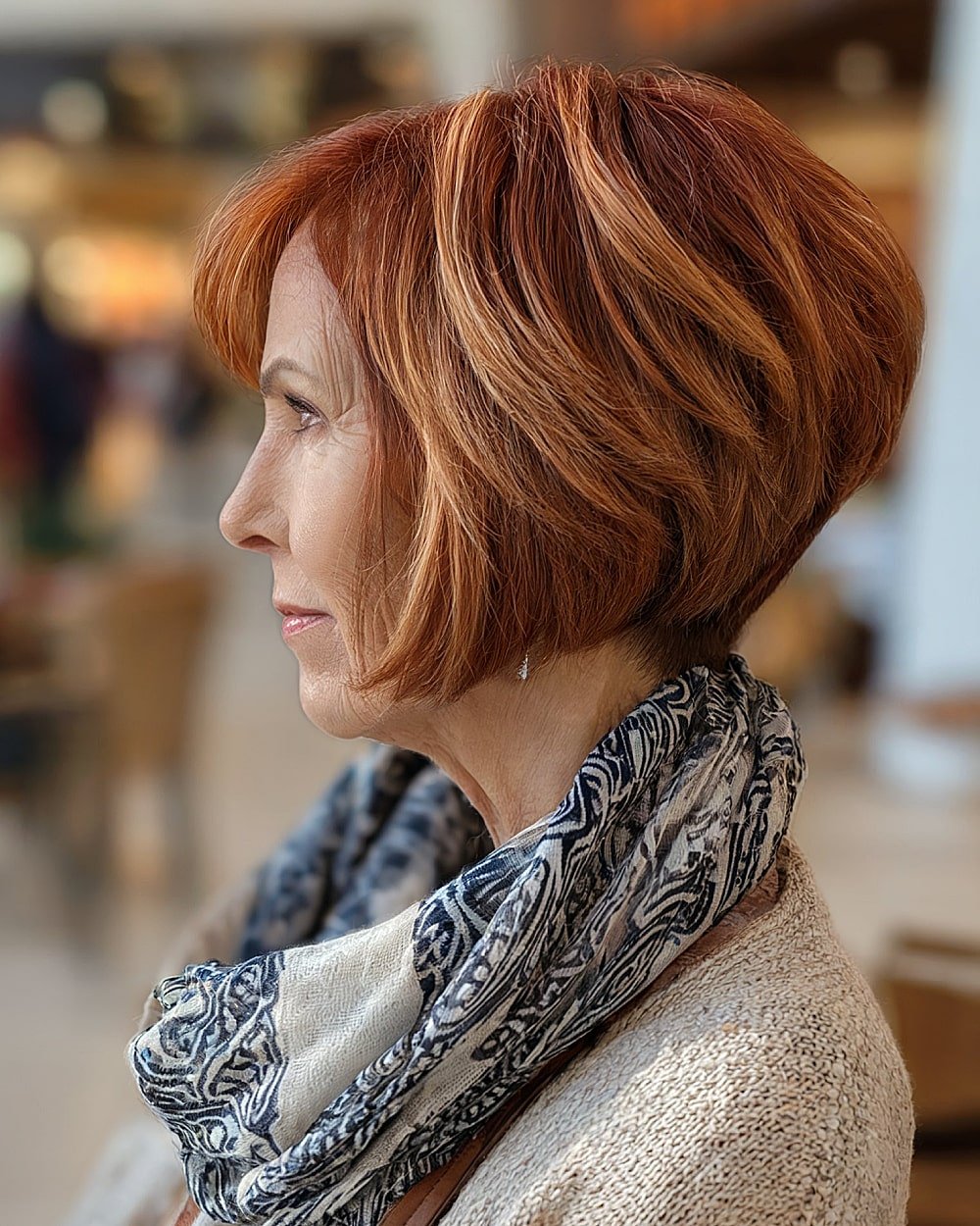 Inverted auburn bob for women over 60 with stacked back and golden red highlights