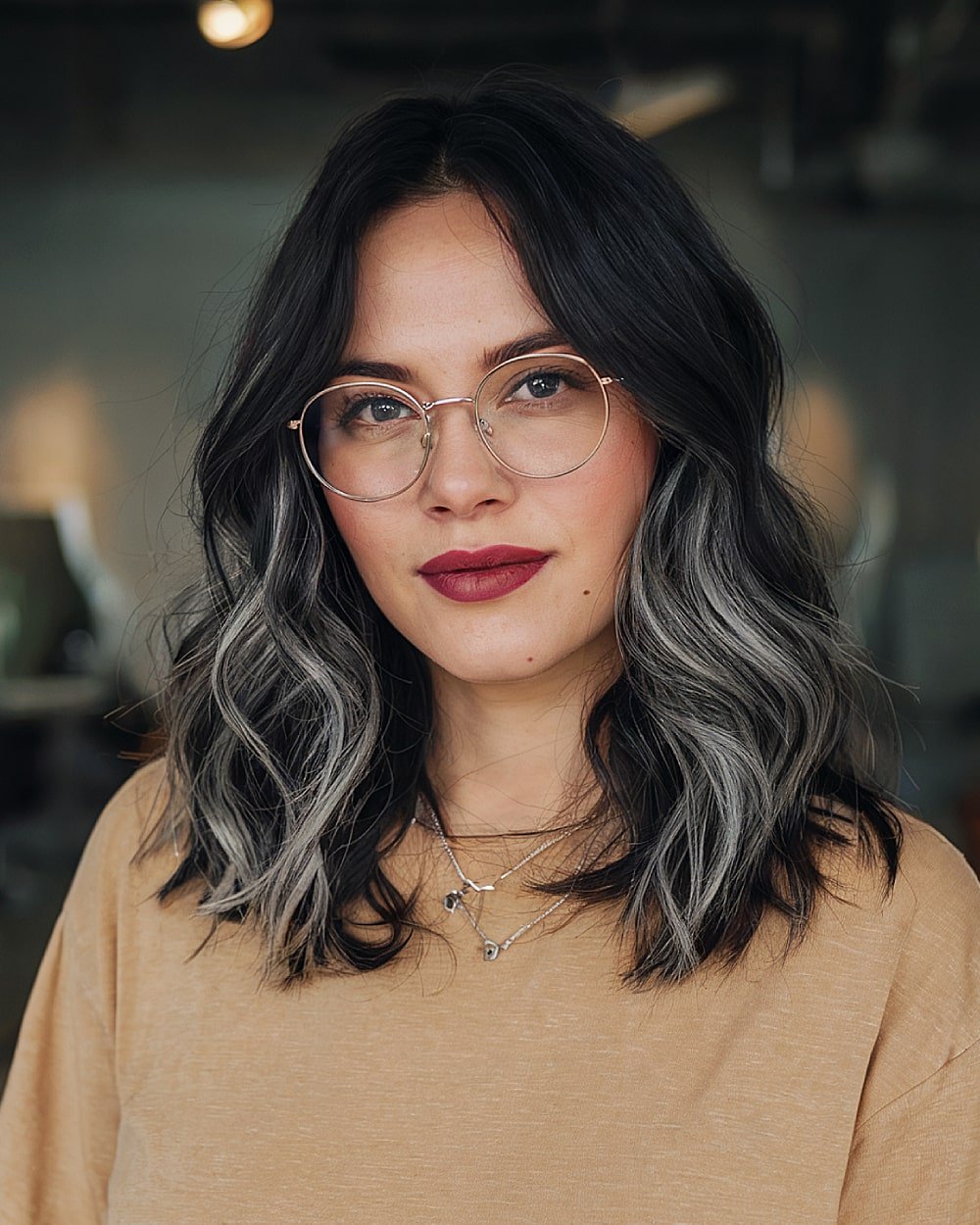 Medium-length dark hair with silver-blended ends and loose waves for low-maintenance grey transition