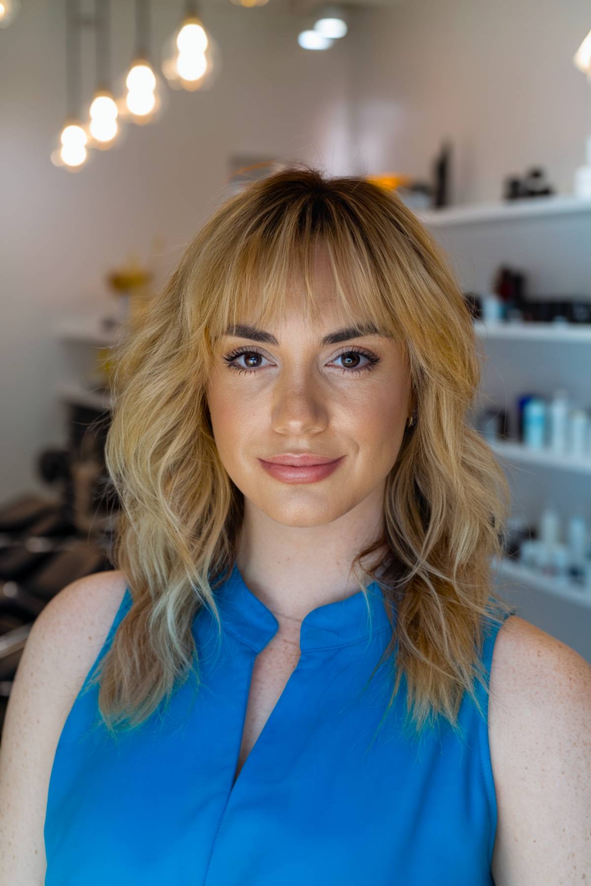 Soft honey blonde waves with airy, decayed bangs for a natural and effortless look
