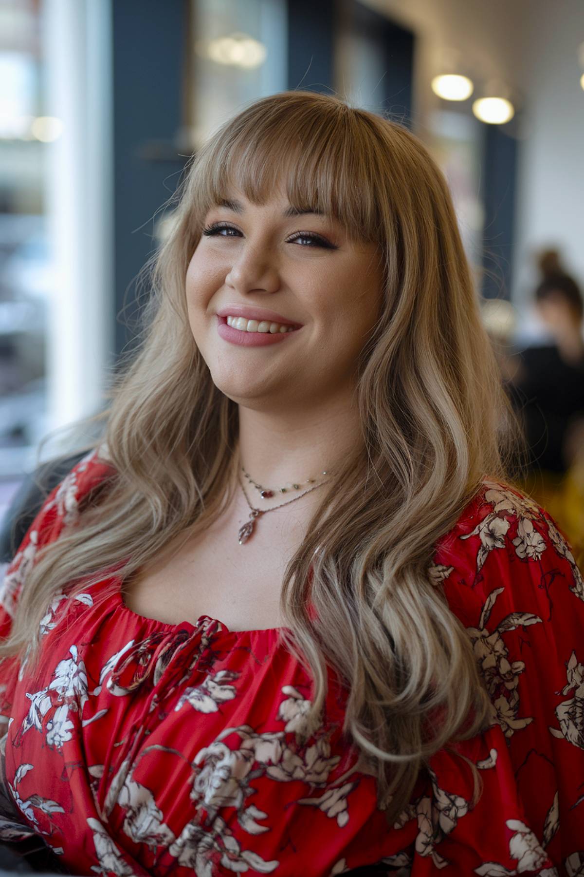 Flowing long blond hair with full bangs that have designed round facial shapes flatter