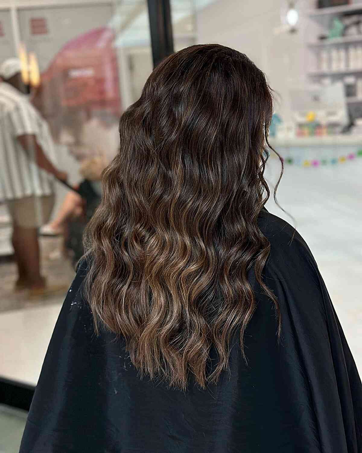Mittel- bis lang schokoladenbraunes Balayage -Haar mit subtilen Toffee -Highlights und welligen Textur
