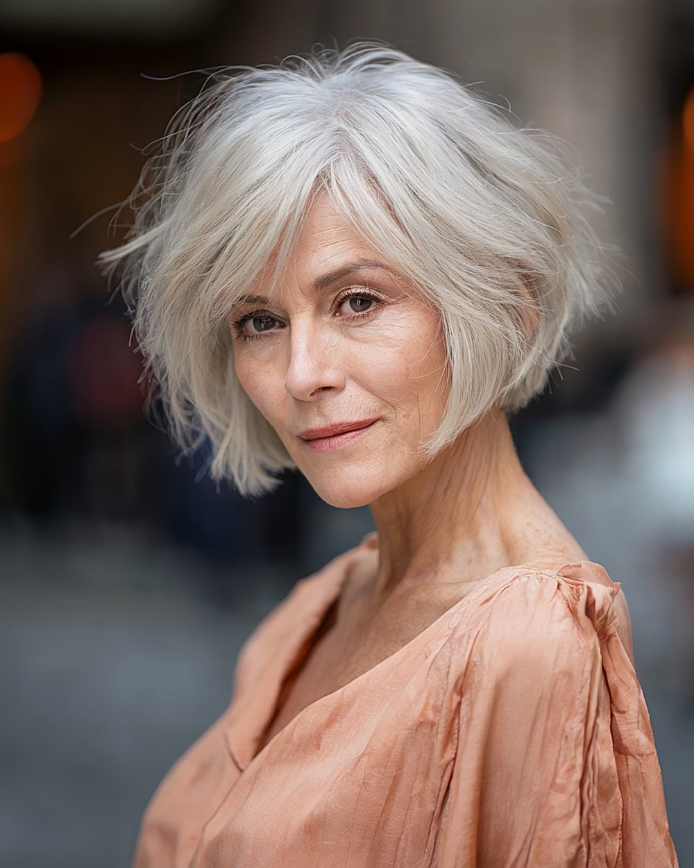 Short stacked inverted bob with choppy crown layers for women over 60 with white hair