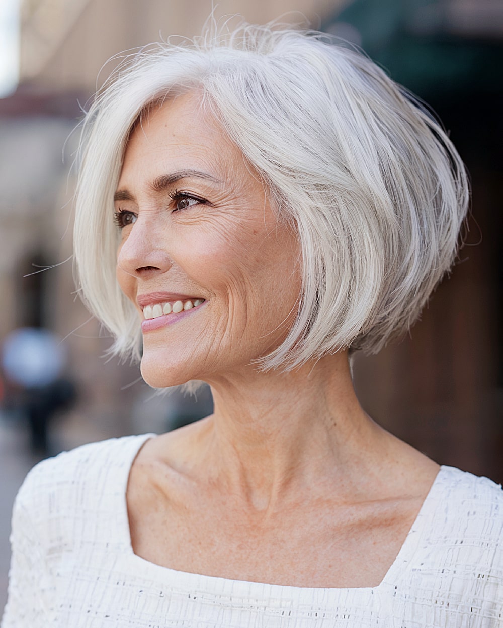 Short layered stacked inverted bob with side-swept bangs for women over 60 with white hair