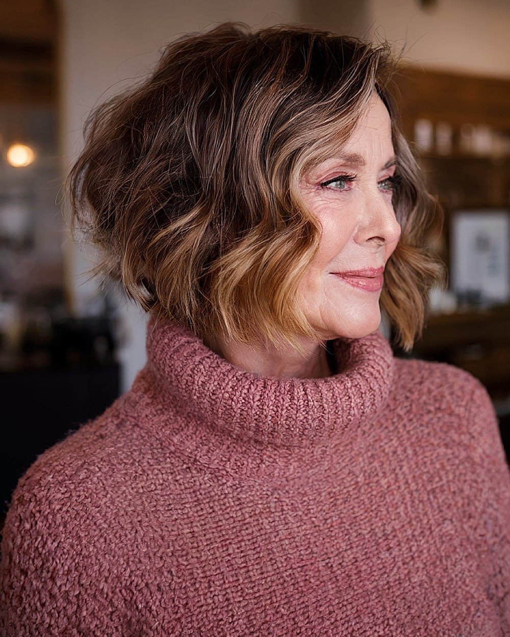 Graduated stacked inverted bob with face-framing layers for women over 60 with wavy hair.