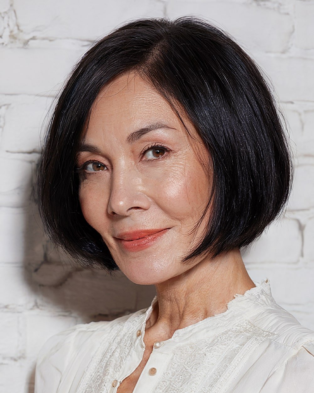 Chin length bob with deep side part on straight black hair for older women