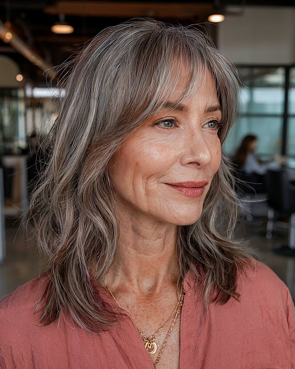 Natural wavy gray hair with fine curtain bangs and medium length layers for mature women