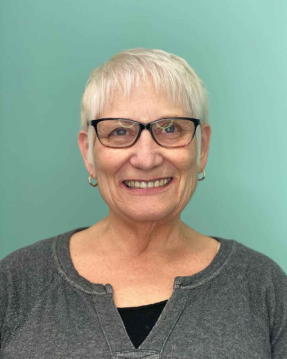 Short snowy blonde haircut with small bangs