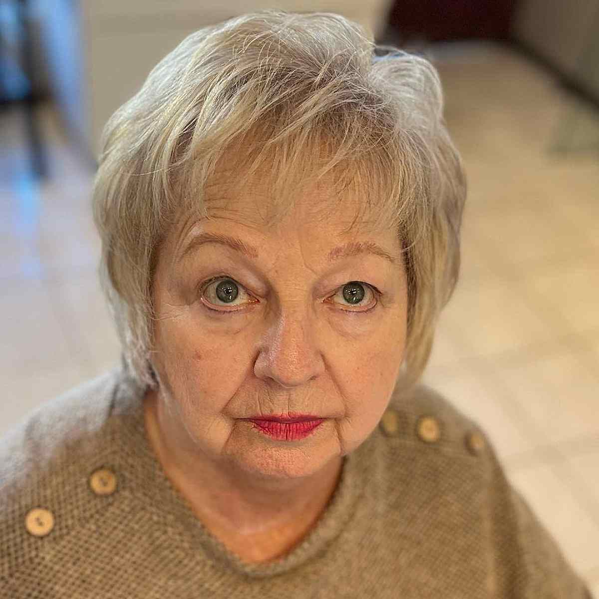 Short, soft blonde hair with feathered layers for women over 60 with round faces
