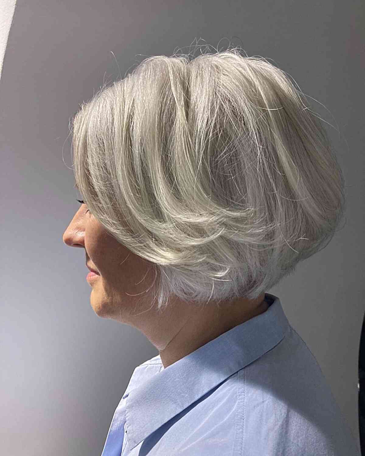 Fluffy jaw-length white bob with feathered layers for older women over 60