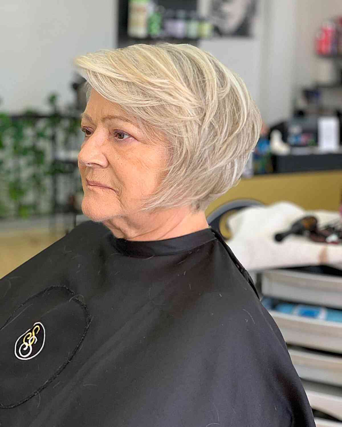 Deep side part of short, jaw-length hair with choppy layers for seniors over 60