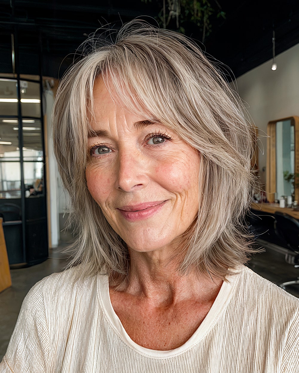 Short haircut for women over 60 with curtain bangs and multi-layered gray strands