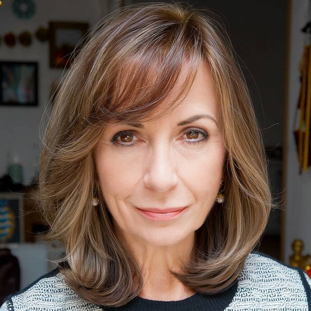A medium-length layered haircut with side bangs, ideal for adding softness and movement to women over 60